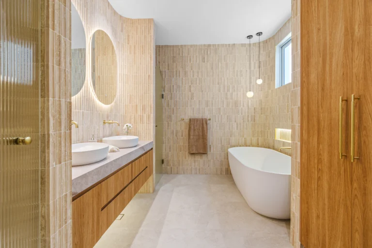 Spa-style bathroom with freestanding tub, warm wood vanity and neutral stone tile