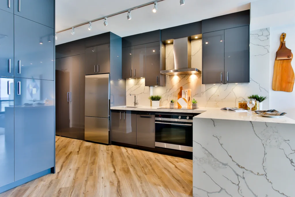 Contemporary kitchen with deep blue cabinetry, marble-look surfaces and wood flooring